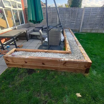 Timber sleeper raised beds with gravel infill built alongside a garden patio
